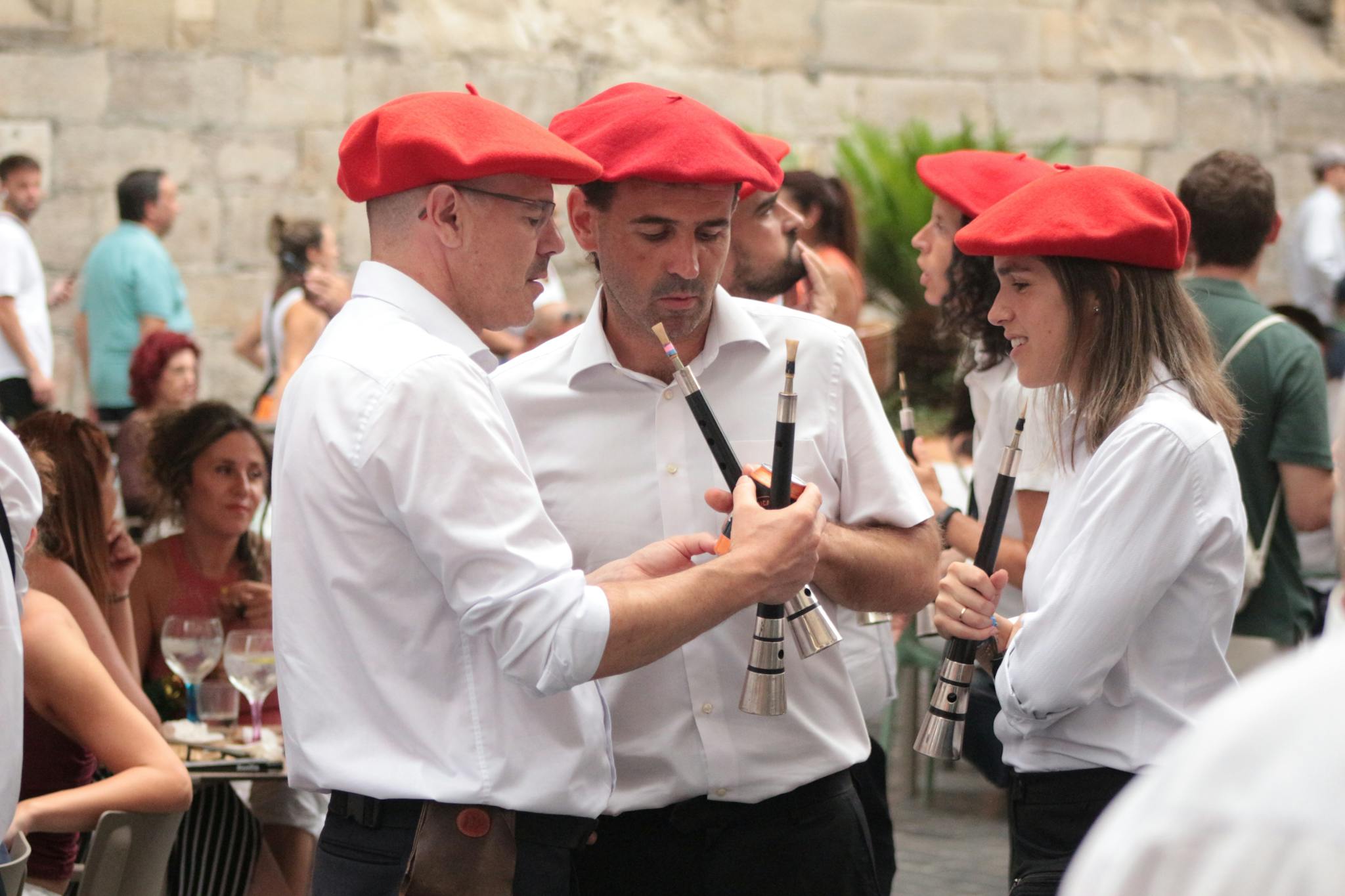 Musicians wearing red berets playing traditional instruments at a Basque festival.