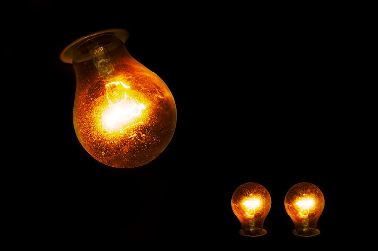 Close-up of illuminated incandescent light bulbs, showcasing warm glowing light against a dark backdrop.