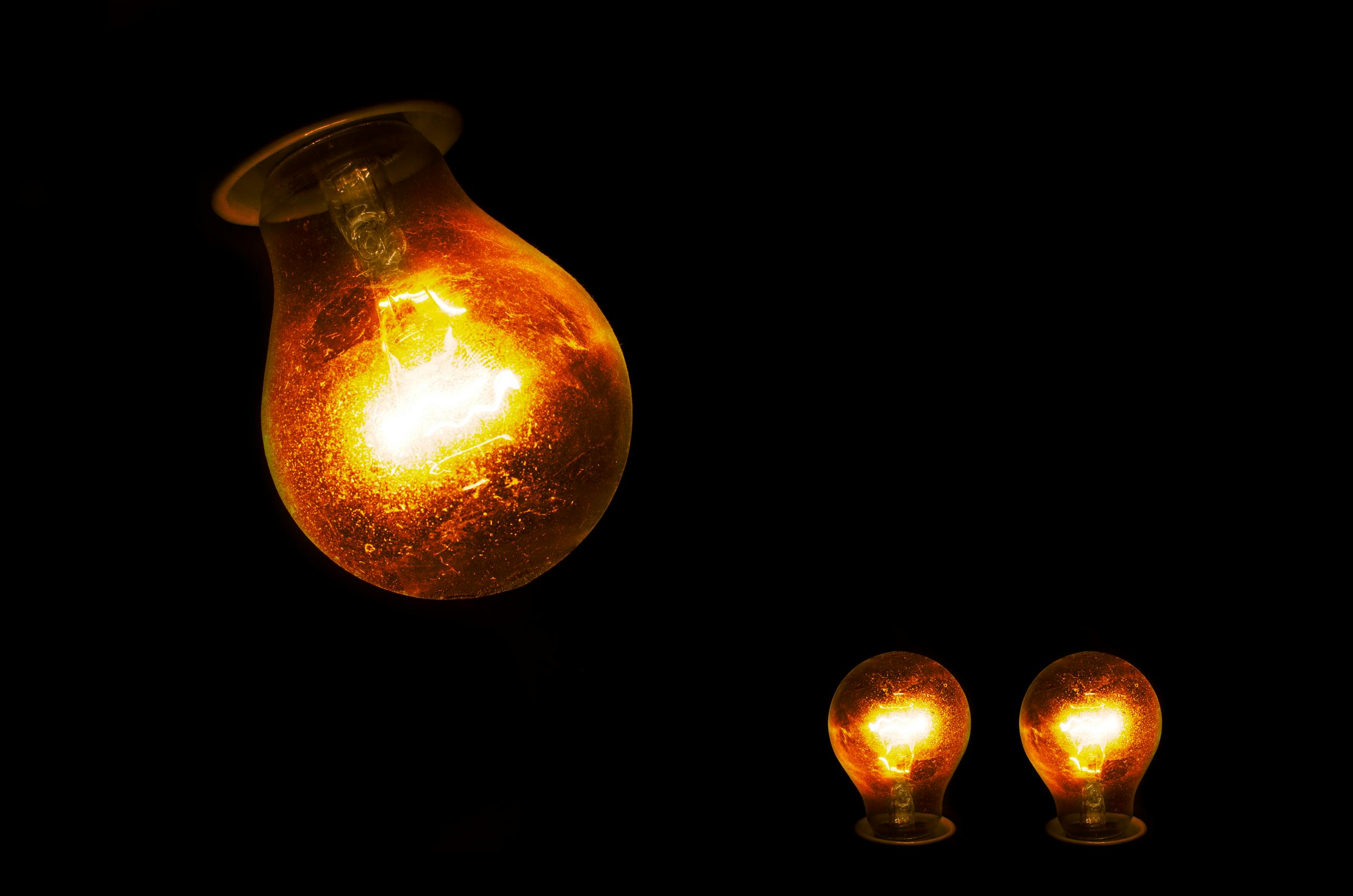 Close-up of illuminated incandescent light bulbs, showcasing warm glowing light against a dark backdrop.
